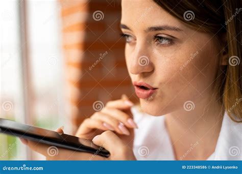 close up of a girl holding a phone near her face and recording a voice message talking on a