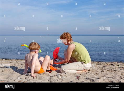 mother helping her son put on his flippers at the beach kuehlungsborn mecklenburg west