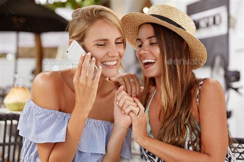 Lovely Lesbian Couple Have Fun Laugh Joyfully And Keep Hands Together Have Mobile Conversation