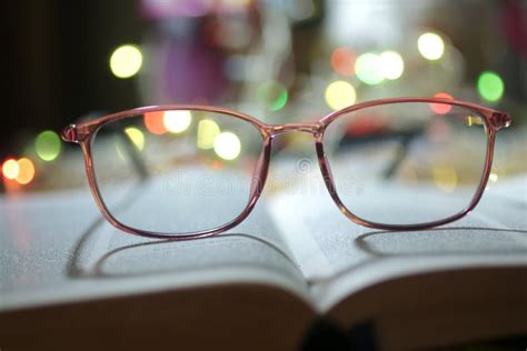 Glasses On Blurry Background Of An Open Book Page And Colorful Bokeh