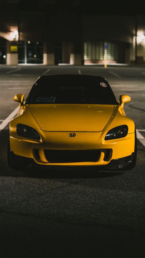 A Yellow Sports Car Is Parked In The Parking Lot At Night With Its