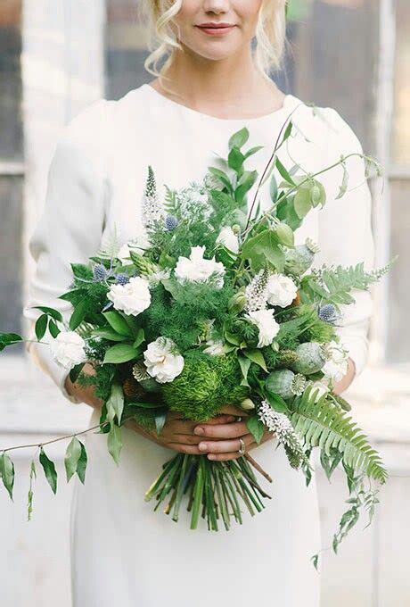A Woman Holding A Bouquet Of Flowers And Greenery