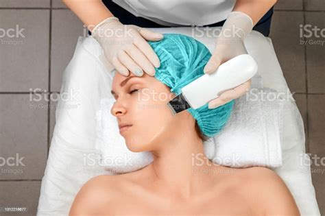 A Gloved Beautician Cleanses The Skin On The Face Using A Special Gel
