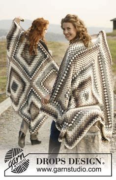 Two Women Walking Down A Dirt Road Holding Up Some Knitted Shawls In