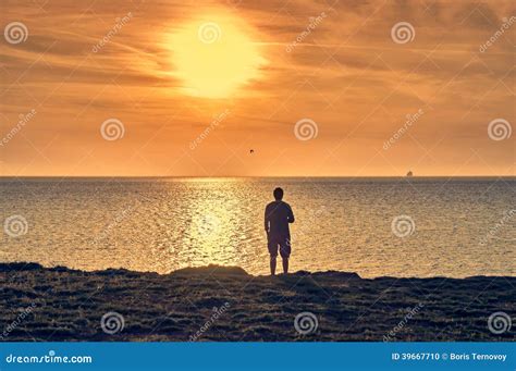 Man Silhouette Standing On A Beach And Watching A Sunrise Stock Photo
