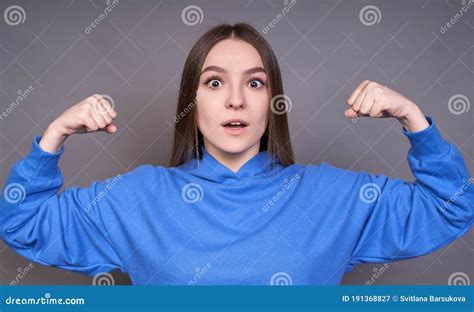 Portrait Of Cheerful Young Girl Bending Biceps Isolated On Gray