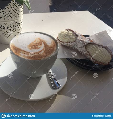 A Delicious Cappuccino Served Next To Fresh Handmade Cannoli Filled