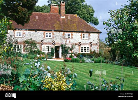 Exterior Of 18th Century Cottage In Sussex Garden With Lawn And Shrubs