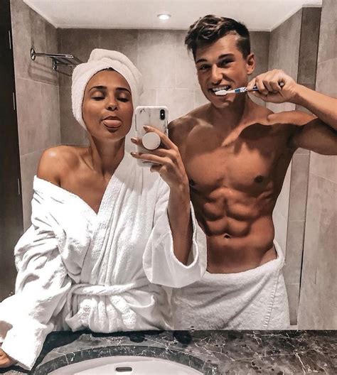 a man and woman brushing their teeth in front of a bathroom mirror while they look at the camera