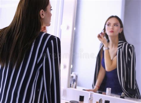 Reflection Of Young Beautiful Woman Applying Her Make Up Looking In A