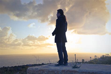 Free Photo Man Wearing Black Coat Standing Near Sea During Golden Hour