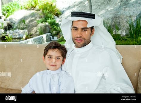 portrait d un père arabe et son fils assis sur le canapé souriant photo stock alamy