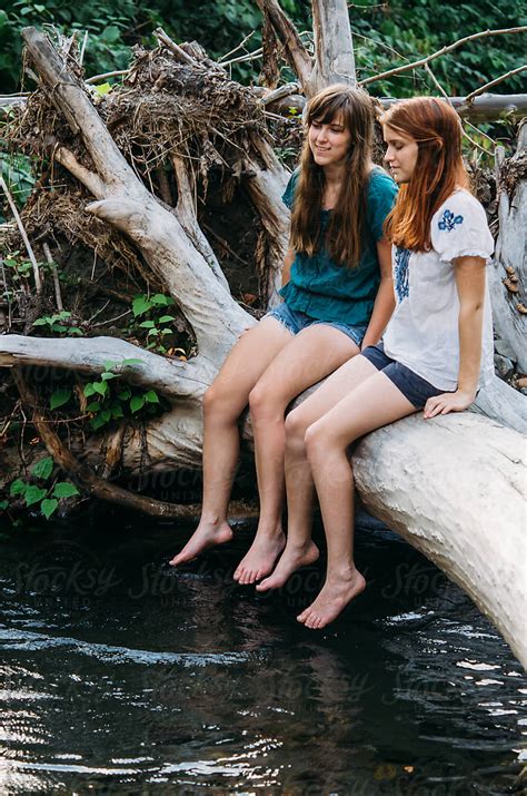 Two Girls On A Log Dangling Feet In Creek By Stocksy Contributor