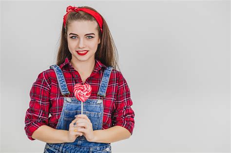Stylish Lovely Girl Holding The Red Heartshape Lollypop On The Stick Looking At The Camera