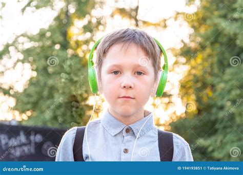 Portrait Of A Schoolboy In Headphones With A Backpack Over His