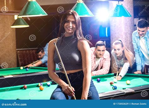 Young Woman Playing In Billiard Posing Near The Table With A Cue In