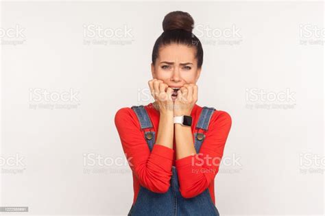 Portrait Of Depressed Nervous Girl With Hair Bun In Denim Overalls