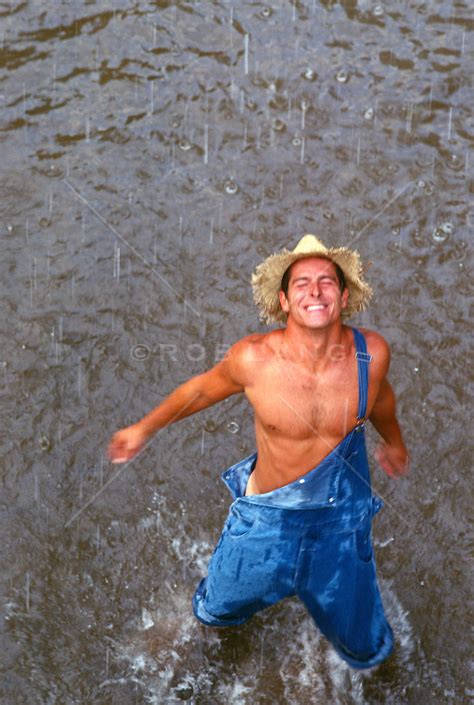 Man In Overalls Enjoying A Rain Shower While Standing In A Stream Rob