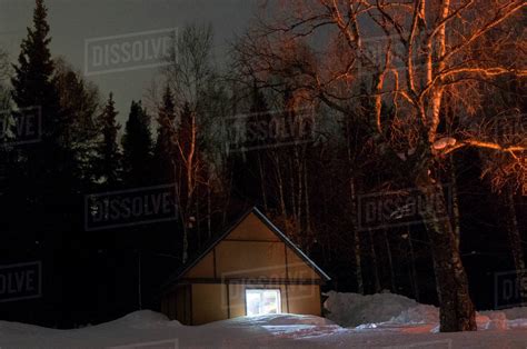Light Glowing In Remote Cabin In Winter Stock Photo Dissolve
