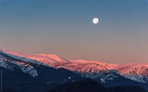 Full Moon Above The Sunrise Snow Mountain Peaks By Stocksy