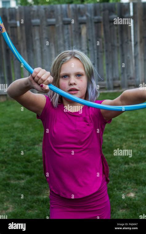 pretty blonde girl playing with hula hoop on the grass in the back yard model release 113
