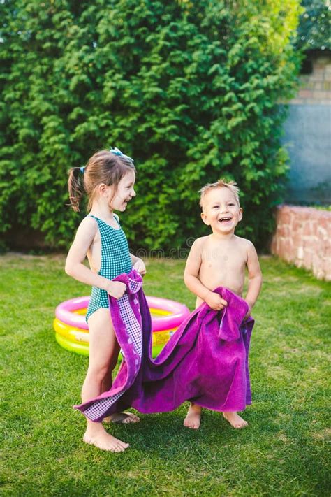 Happy Caucasian Children Play Wrapped In A Large Summer Beach Towel In