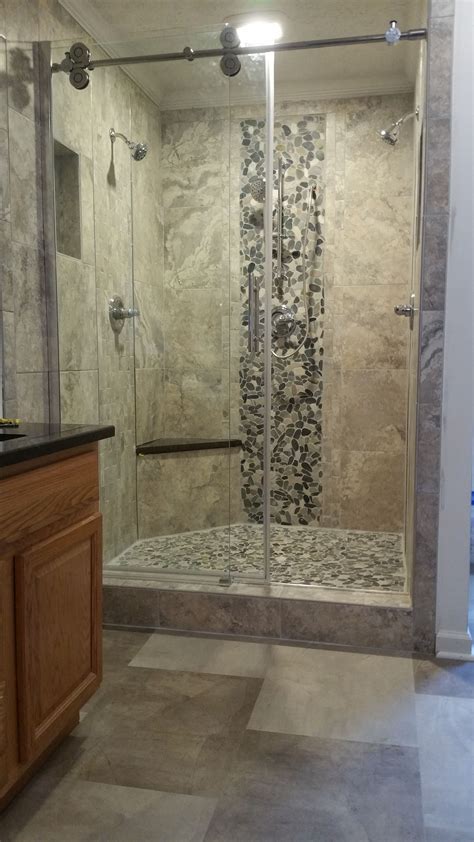 custom shower using large format gray porcelain tile featuring multiple heads and a granite seat