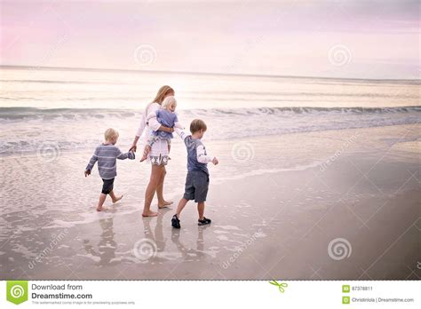 Mother And Children Walking Along Ocean Beach At Sunset Stock Image