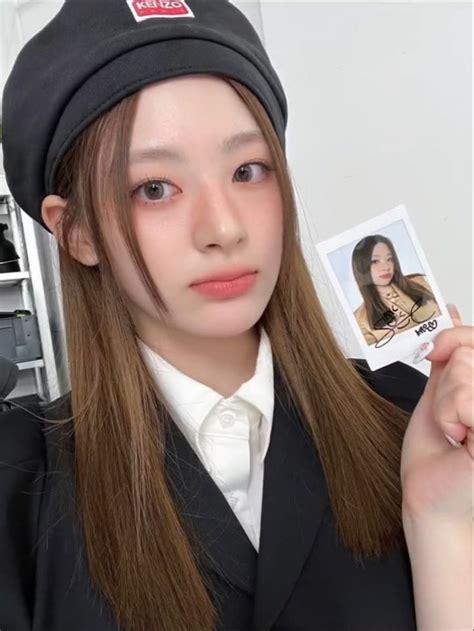 a girl with long brown hair holding up a photo and wearing a black beret