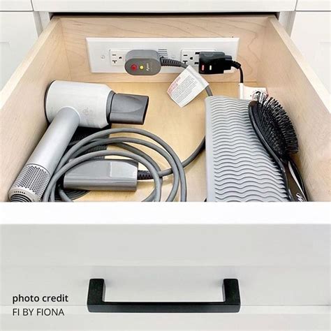 An Open Drawer With Hair Dryers And Other Items In The Bottom Part Of It