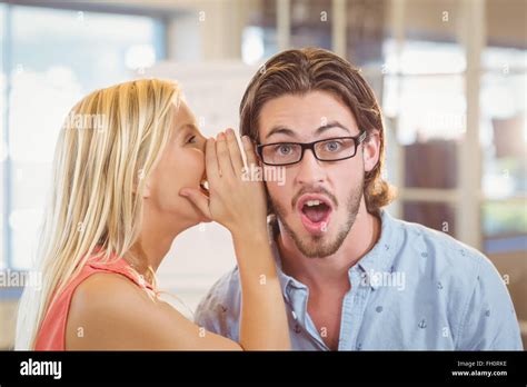 Businessman listening to rumor which female colleague is whispering ...