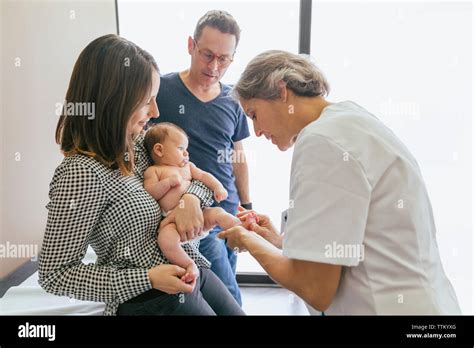 Female Doctor Examining Baby Boy With Parents At Hospital Stock Photo