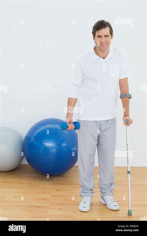 Portrait Of A Smiling Man With Crutch And Dumbbell Stock Photo Alamy