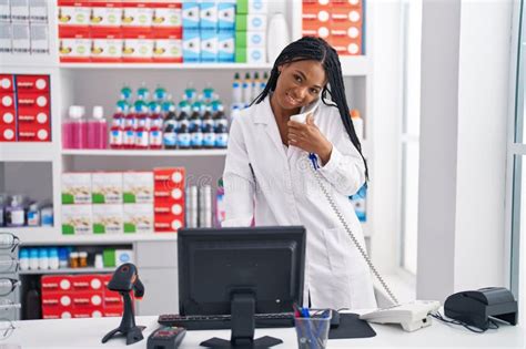 African American Woman Pharmacist Talking On Telephone Using Computer