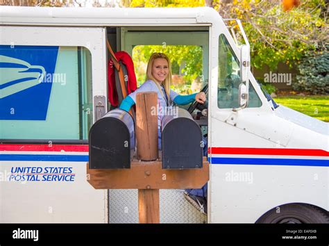 Female United States Postal Service Carrier Delivering Mail In