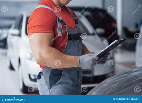 Handsome Young Auto Mechanic In Uniform Is Examining Car In Auto