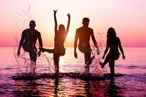 Happy Friends Splashing Water On Tropical Beach At Sunset Group Of