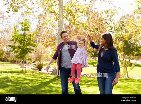 Mixed Race Couple Lifting Up Their Young Daughter In Park Stock Photo