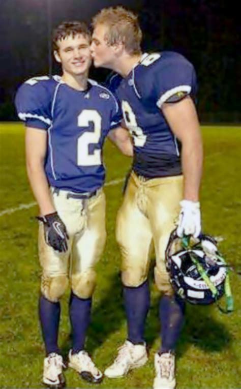 Two Football Players Standing Next To Each Other On A Field