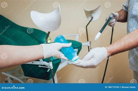 Proctologist Holding An Anoscope Against A Proctological Chair Stock