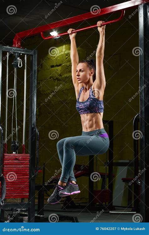 fitness girl doing pulls up on horizontal bar in gym muscular woman abs shaped abdominal