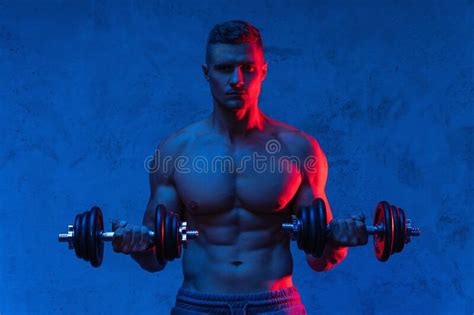 Muscular Bodybuilder Man Exercising With Dumbbells In Colorful Neon