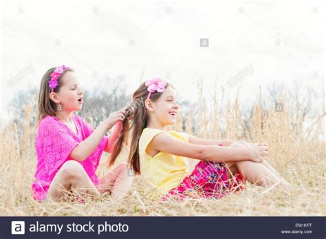 3 sister's african hair braiding. Girl braiding sister's hair in meadow Stock Photo ...