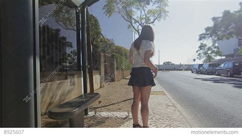 Lonely Young Girl Waiting Staying At Bus Stop With Smart Phone In Blue