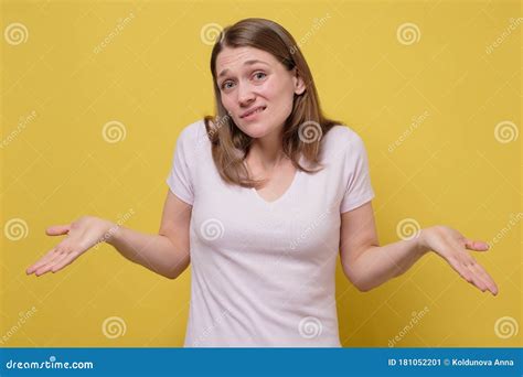 Attractive Young Woman Shrugging Her Shoulders On Yellow Wall Stock