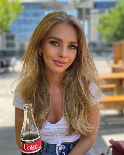 a woman is holding a coke bottle and posing for the camera