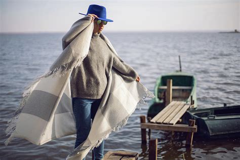 Woman In Jeans And A Sweater And A Hat Stands On A Pier With Boats By Lake In Autumn Photograph