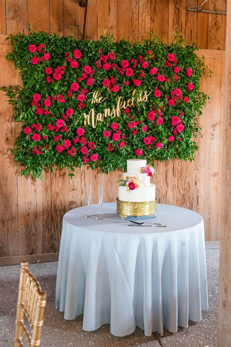 A Wedding Cake Sitting On Top Of A Table Next To A Wooden Wall Covered