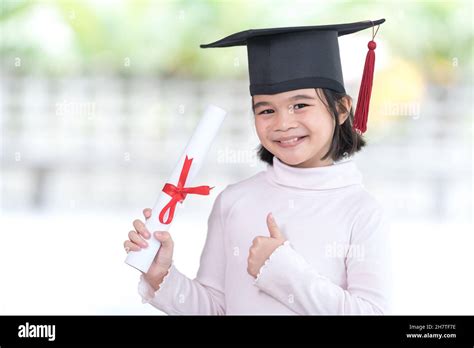Happy Southeast Asian Schoolgirl With A Certificate Celebrating Graduation In Thailand Stock