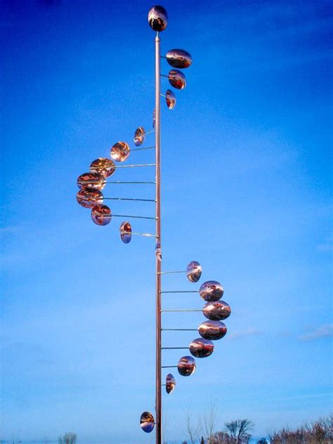 A Tall Metal Pole With Lots Of Balls Hanging From Its Sides In Front